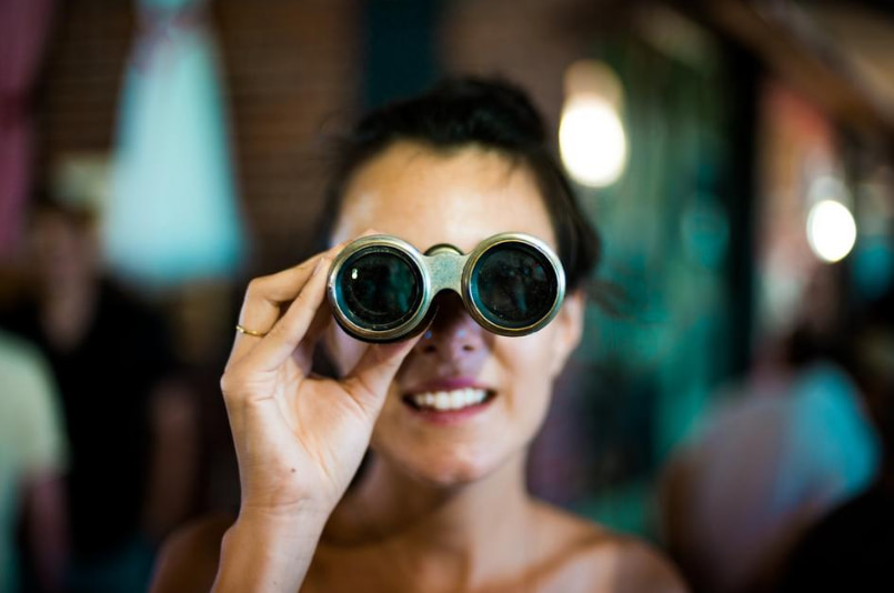 Primer plano de la cara de una mujer observando a través de unos prismáticos